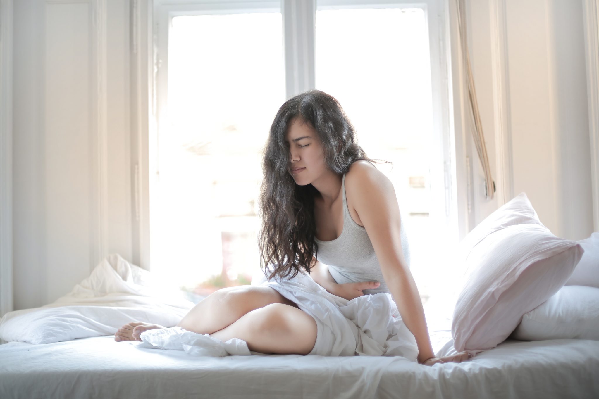 femme allongée lit douleur ventre gonflé et dur